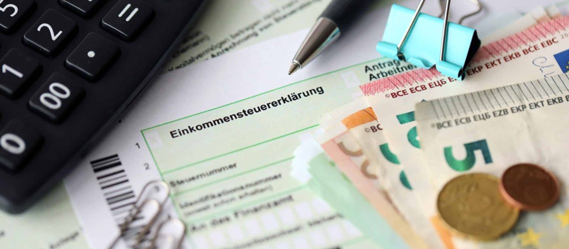 German income tax return form with pen and european euro money bills lies on accountant table close up. Taxpayers in Germany using euro currency as main to pay taxes