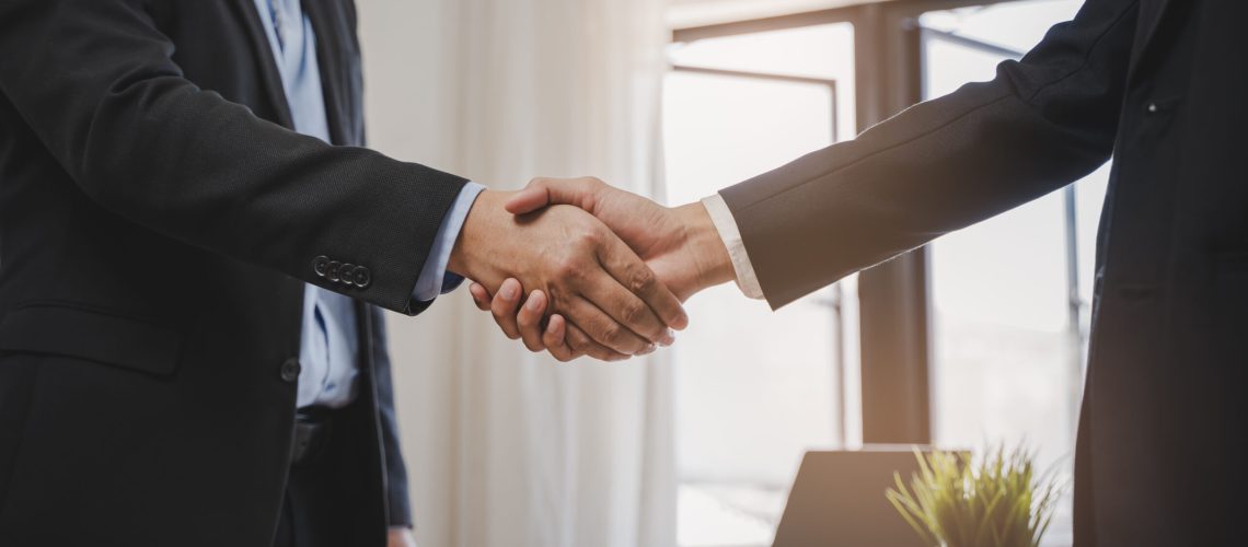 close-up view hands of agent and client shaking hands after signed contract buy new apartment.